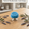 Blue flower shaped hyaluronic acid soap on stand with lavender sprigs on wood table.