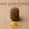 Single oval organic gram flour soap with a leaf imprint and a small pile of besan powder below it.