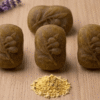 Four oval gram flour soap bars with a pile of raw besan powder on a wooden table.