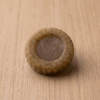 A single round textured gram flour soap bar on a plain wooden background.